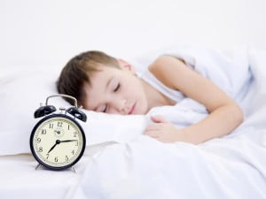 kid sleeping with clock showing time